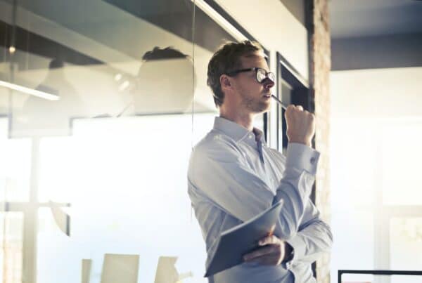 Thoughtful professional holding a tablet, symbolizing transition and strategic planning.